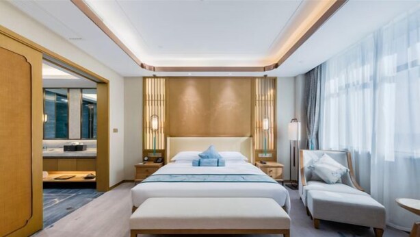 Een moderne hotelkamer met een groot bed, een zithoek en uitzicht op de stad.