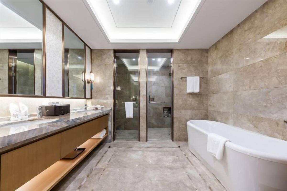 Een moderne badkamer met een grote spiegel, een badkuip en een douchehoek.