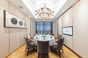 A conference room with a round table, chairs, a chandelier, and framed artwork on the walls.
