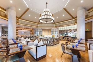 A spacious hotel lobby with multiple seating areas, a central bar, and a chandelier.