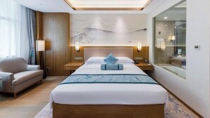 Hotelkamer met een bed, een slaapbank, een nachtkastje, een lamp en een schilderij aan de muur.