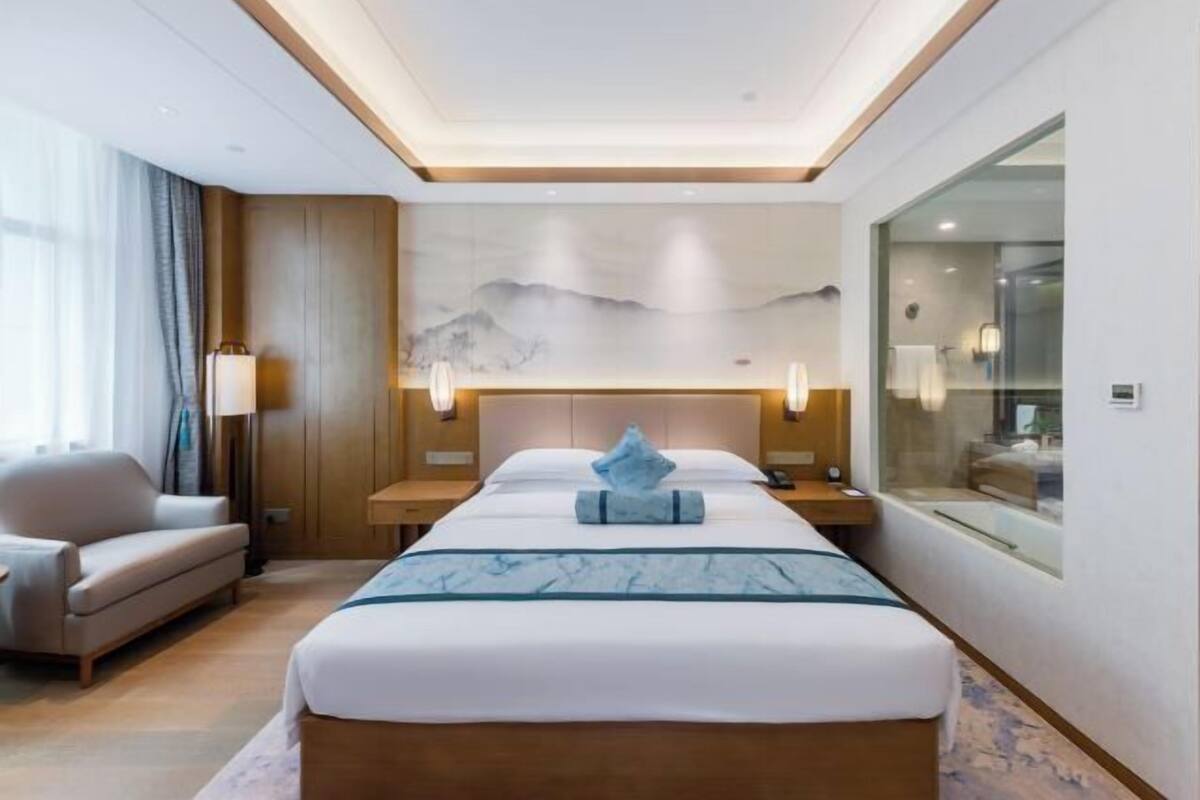 Hotelkamer met een bed, een slaapbank, een nachtkastje, een lamp en een schilderij aan de muur.