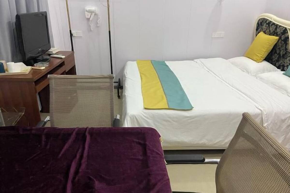 Una habitación de hotel con cama, escritorio con televisor y una silla.