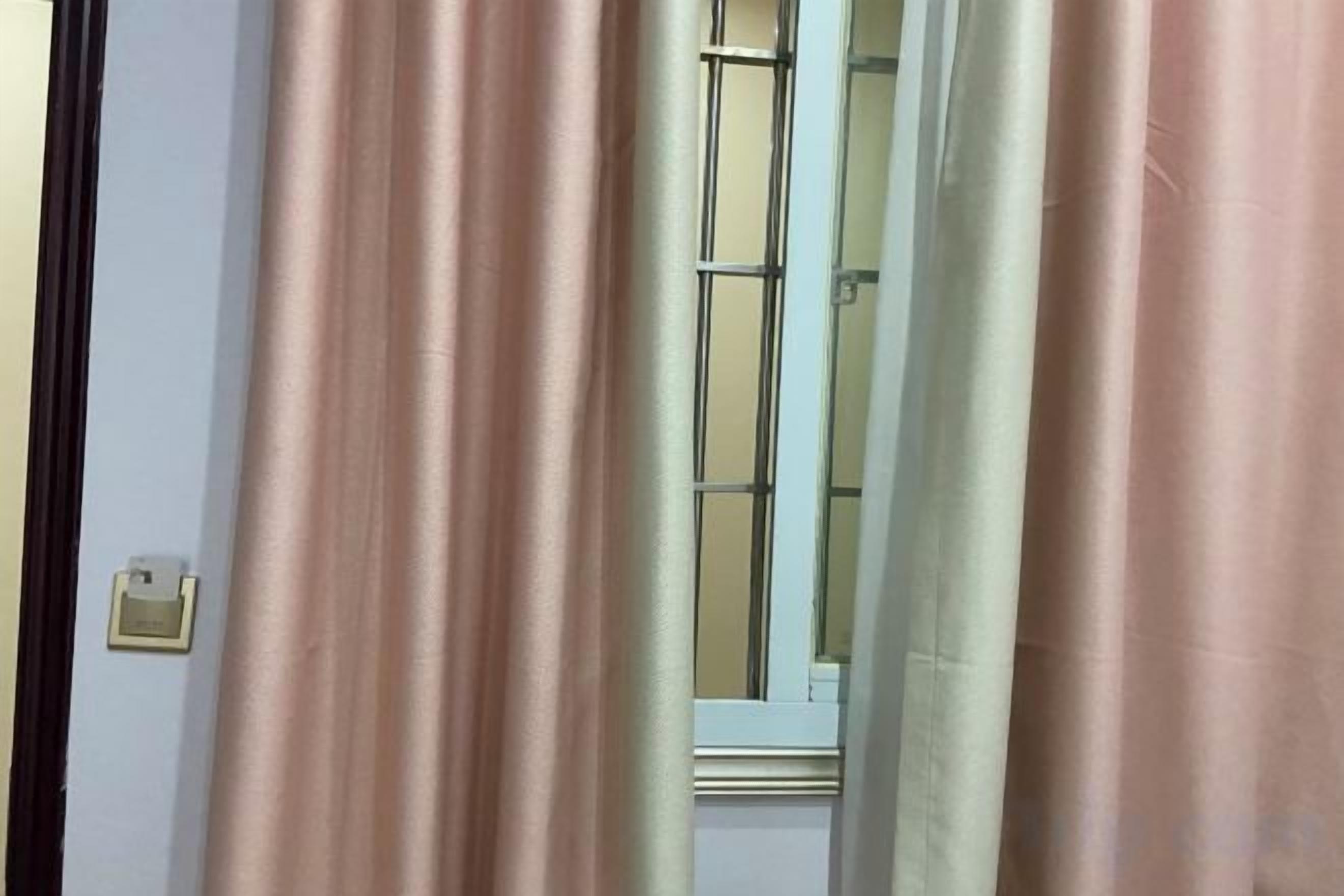 Una habitació amb finestra, cortines i porta.