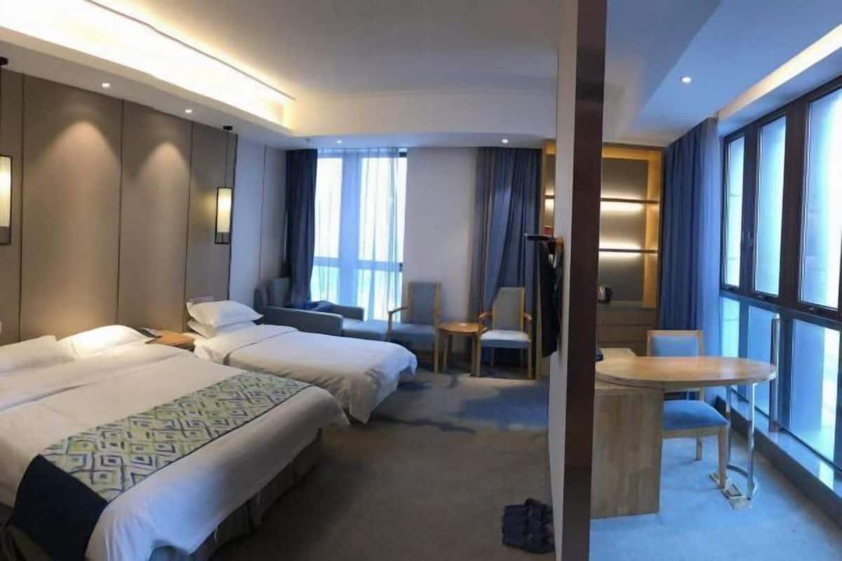 Ein Hotelzimmer mit zwei Betten, einem kleinen Tisch und einer Sitzecke mit Sesseln.