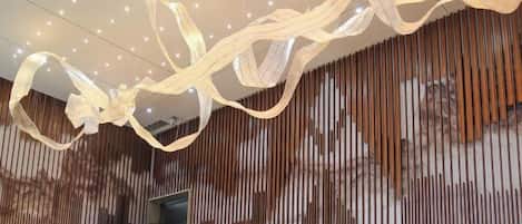 Un interior moderno con un muro de listones de madera, una escalera mecánica y un techo con lámparas colgantes.