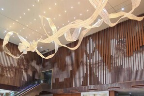 A modern interior with a wooden slat wall, an escalator, and a ceiling with hanging light fixtures. - Daxinjunlan Hotel (Hai'an)
