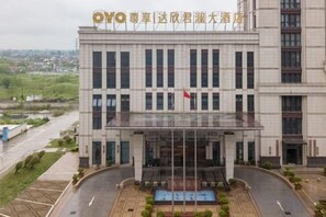 A modern building with a large entrance, a flag, and a pool area. - Daxinjunlan Hotel (Hai'an)