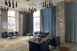Un vestíbulo de hotel con zonas de estar, ventanas amplias y una alfombra estampada.