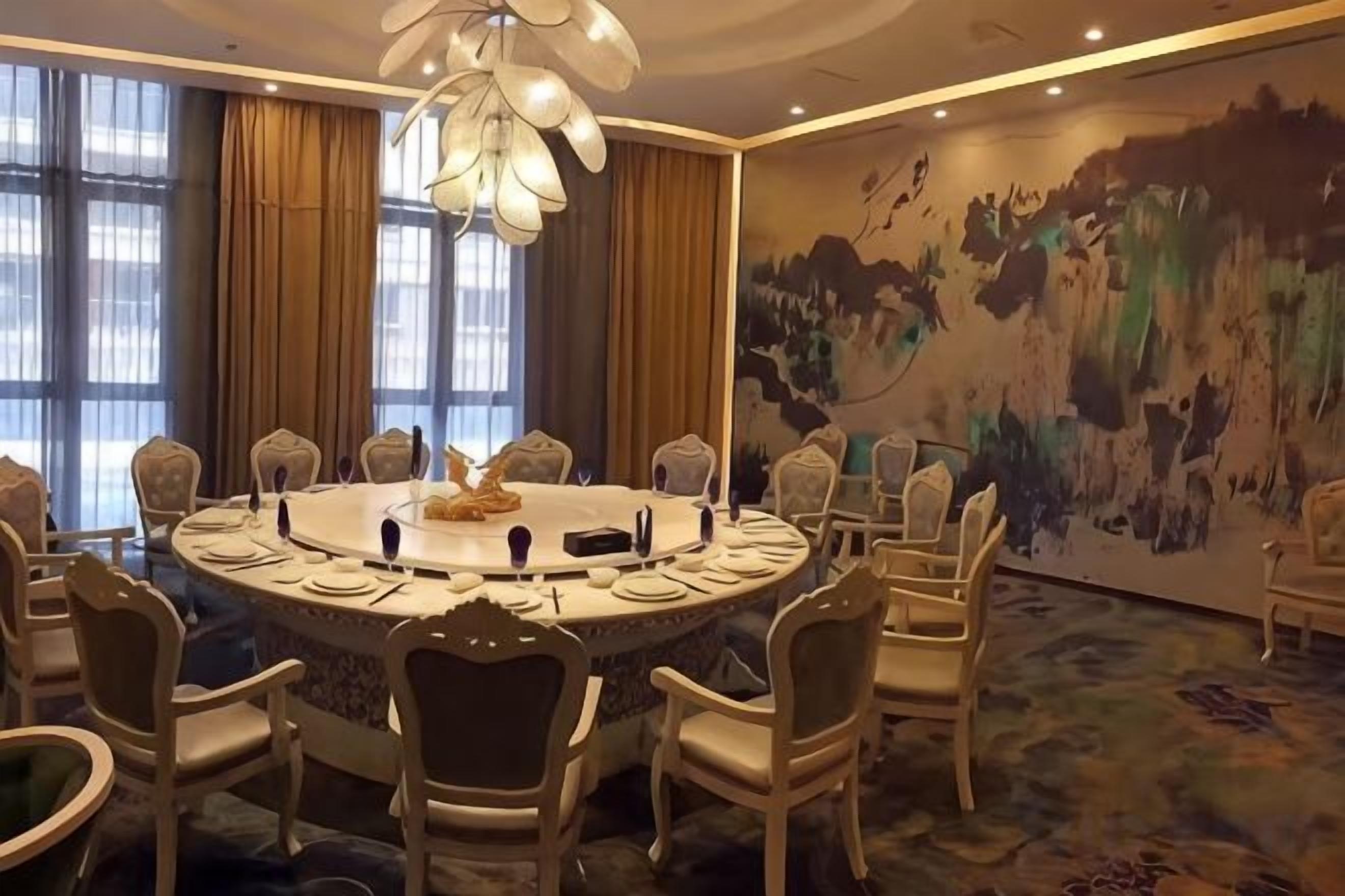 A conference room with a round table, chairs, and a chandelier.
