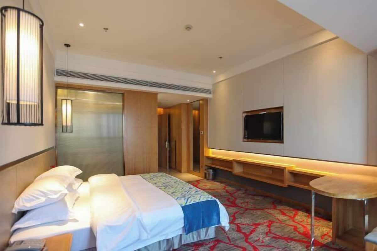 Ein Hotelzimmer mit Bett, Nachttisch, Fernseher und Spiegel.