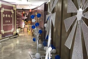 A hotel corridor with a decorative wall, a metallic structure with balloons, and a patterned floor. - Daxinjunlan Hotel (Hai'an)
