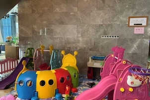 Un área de juegos infantiles con diversas estructuras de juego coloridas, incluyendo un tobogán y juegos de escalada.