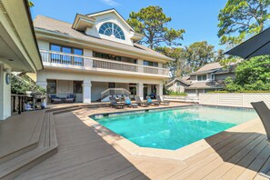 A two-story house with a swimming pool, outdoor furniture, and a covered patio area.