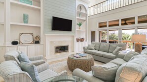 Un salón amplio con chimenea, asientos cómodos y un televisor grande.