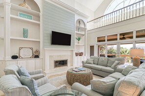 A spacious living room with a fireplace, comfortable seating, and a large TV.
