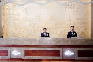 Dos recepcionistas en un mostrador de recepción con un detallado relieve en la pared detrás.