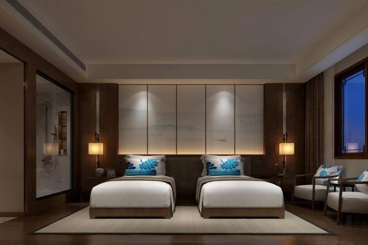 A hotel room with two beds, a large window, and a wall-mounted cabinet.