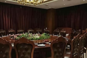 A conference room with a round table, chairs, and a floral centerpiece.