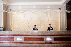 A reception desk with two staff members, a detailed wall mural, and a modern reception area.