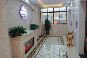 A hotel lobby with a marble fireplace, potted plants, a large window, and a decorative statue. - Xiangdu Hotel (Jinxi)