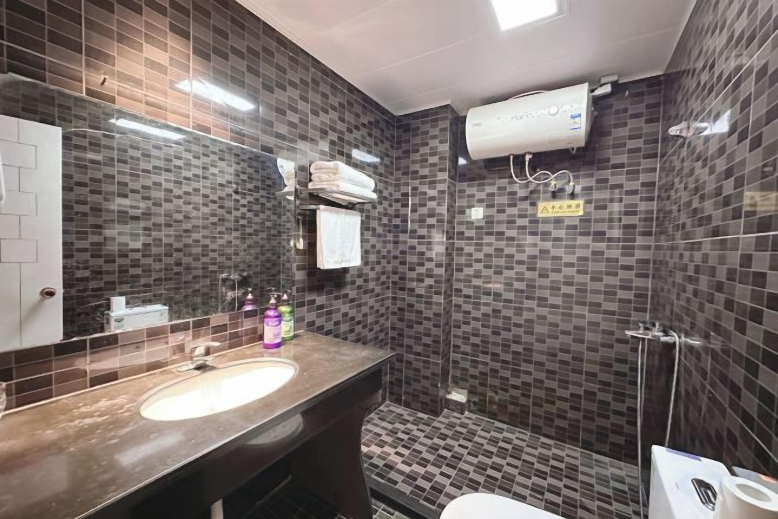 A bathroom with a sink, mirror, towel rack, and a shower area.