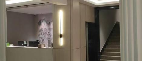A modern interior with a reception desk, a staircase, and a dining area.