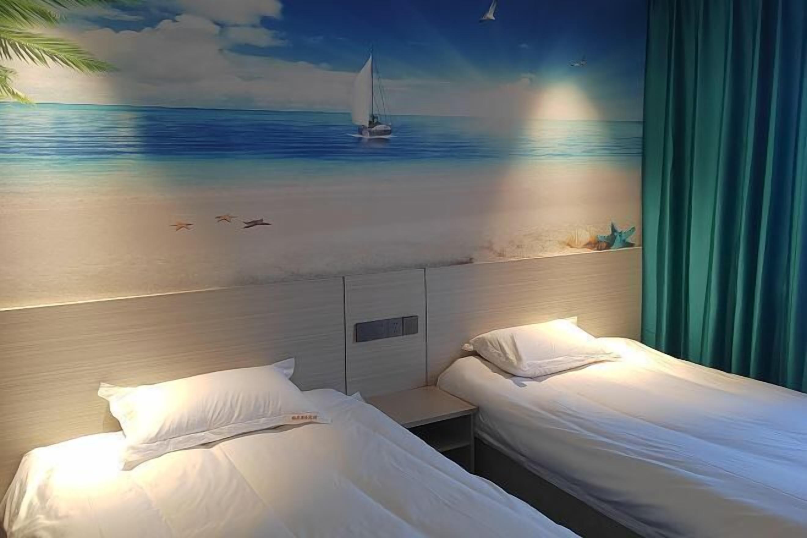 Une chambre d’hôtel avec deux lits, un tableau représentant une scène de plage et une vue sur l’océan.