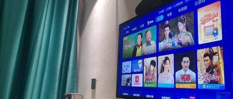 A television mounted on a wall displaying a selection of movie and TV show thumbnails.