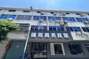A building with multiple floors, air conditioning units, and a storefront with a sign. - JYhotel (Yuyao)