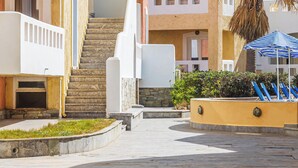 A hotel courtyard with a central staircase, palm trees, and outdoor seating.