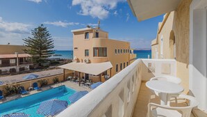 A balcony with a pool, lounge chairs, and umbrellas.
