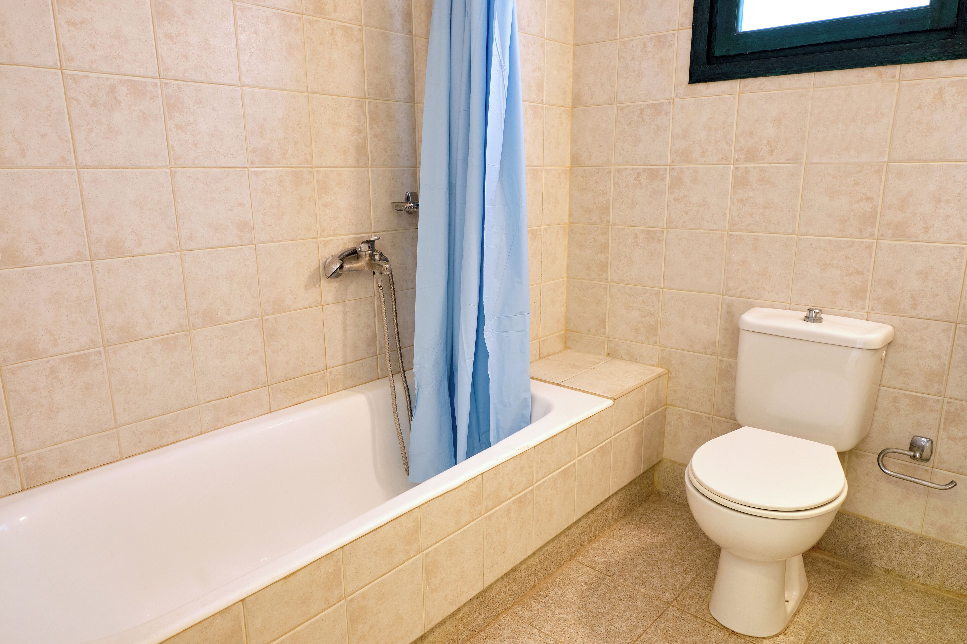 A bathroom with a bathtub, toilet, and a window above the toilet.