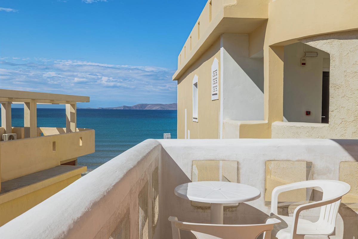 A balcony with a table and chairs overlooking the sea.