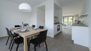 A modern kitchen with white cabinets, a built-in oven, and a small island with a sink. - Apartment with 3 bedrooms and private sauna (Rohrmoos-Untertal)