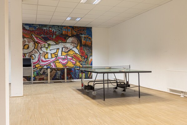 An indoor space with a ping pong table, a colorful graffiti wall, and a white radiator. - Apartment with 3 bedrooms and private sauna (Rohrmoos-Untertal)