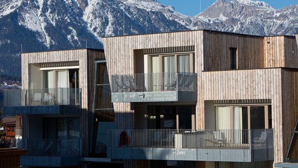 A modern wooden building with balconies and large windows, set against a mountainous backdrop. - Apartment with 3 bedrooms and private sauna (Rohrmoos-Untertal)