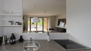 A modern kitchen with a built-in sink, a dining area with a table and chairs, and a view of a balcony with outdoor seating. - Apartment with 3 bedrooms and private sauna (Rohrmoos-Untertal)