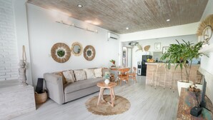 Un salon moderne avec un canapé, une table basse et des miroirs décoratifs. Il y a également un coin cuisine équipé d’un réfrigérateur et une table à manger.