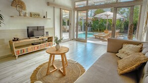 Un salon spacieux avec une grande télévision, un canapé et une table basse.