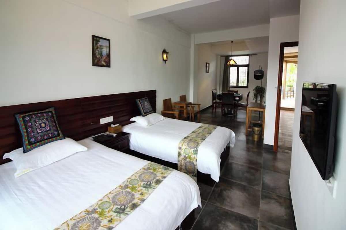 A hotel room with two beds, a dining area, and a TV.