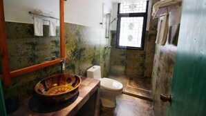 A bathroom with a large bowl sink, a toilet, and a shower area.