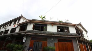 A traditional building with a tiled roof, wooden doors, and potted plants.
