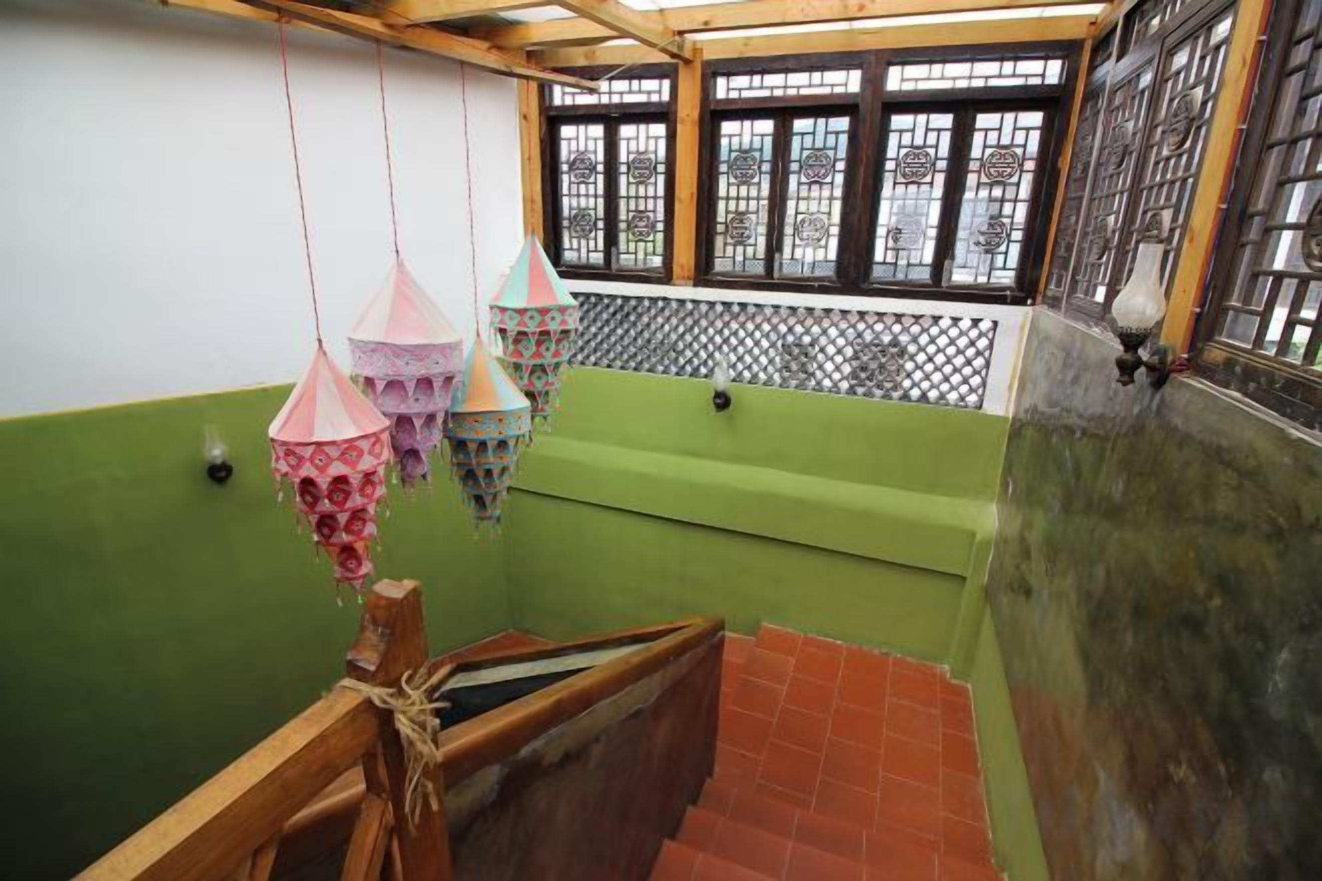 A room with a green wall, a wooden bench, and hanging decorative items.