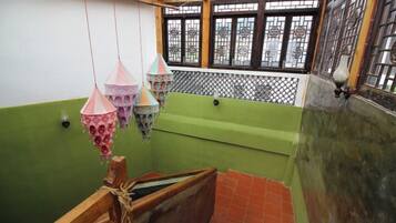 A room with a green wall, a wooden bench, and hanging decorative items.