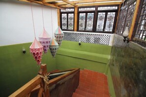 A room with a green wall, a wooden bench, and hanging decorative items. - Reshui Impression Inn (Rucheng)