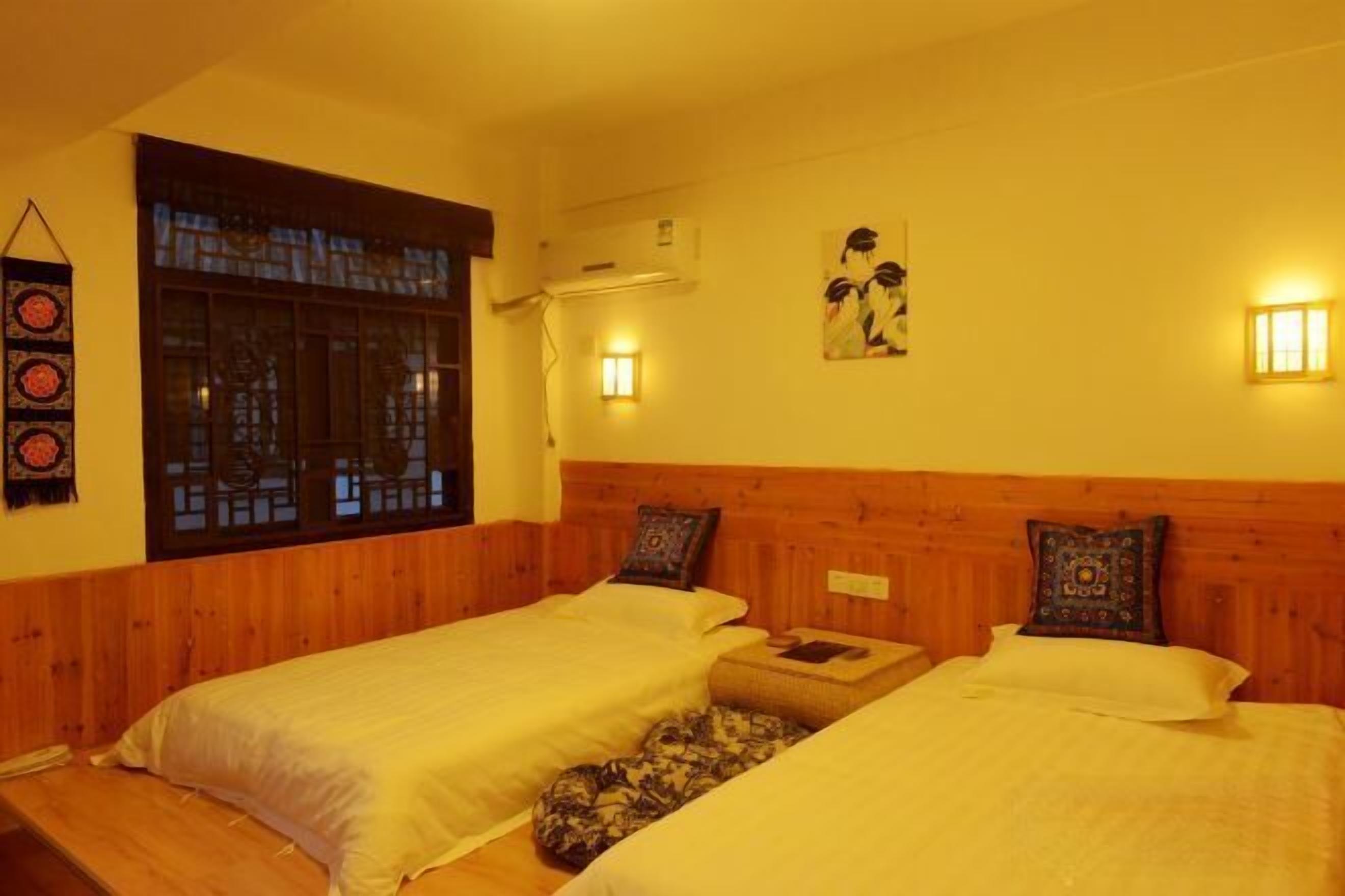 A room with two beds, a window with a view, wall-mounted lights, and a wall decoration.