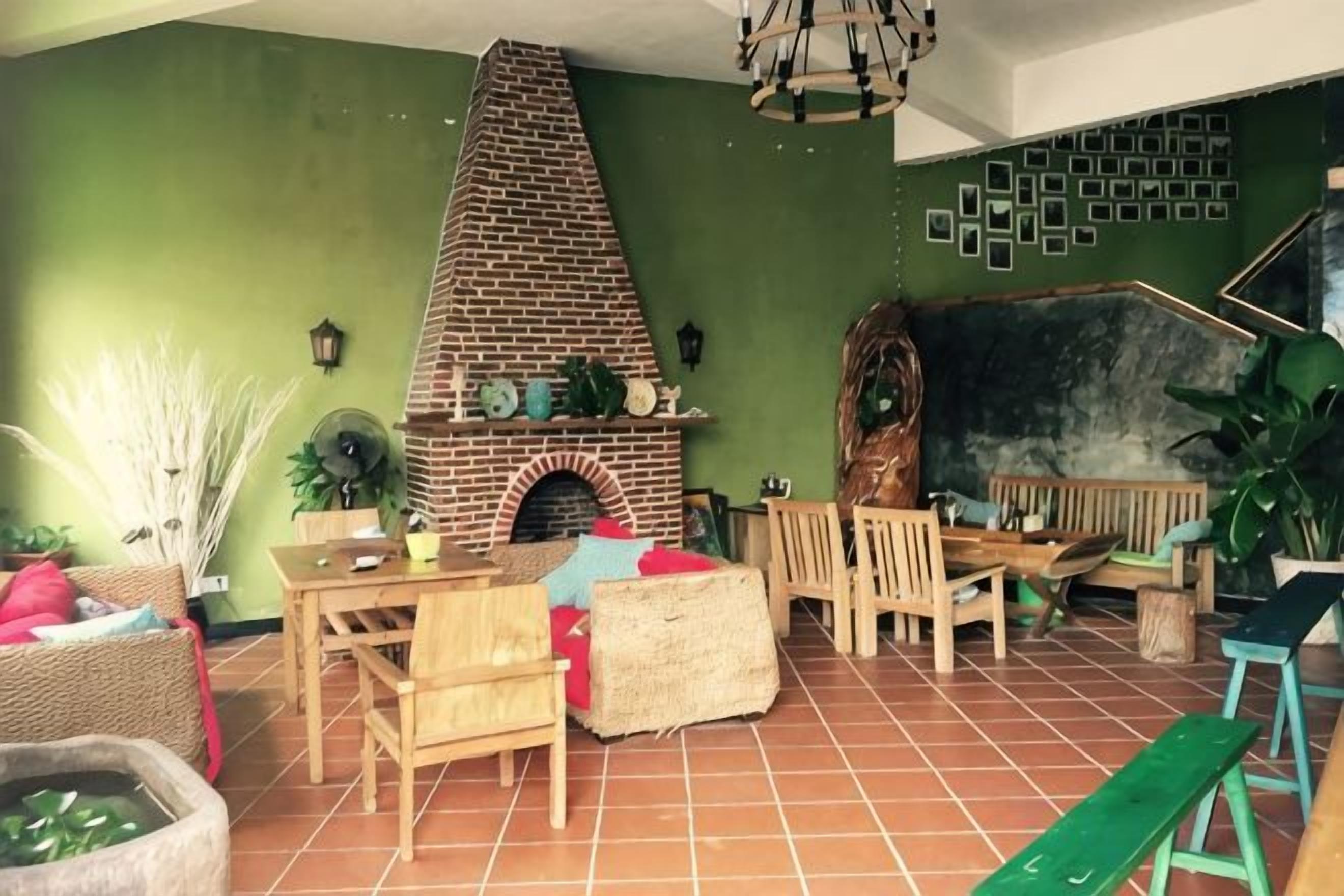 A room with a brick fireplace, wooden furniture, and green walls.