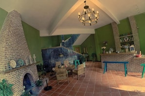 Una habitación con chimenea de ladrillo, candelabro y pared verde.
