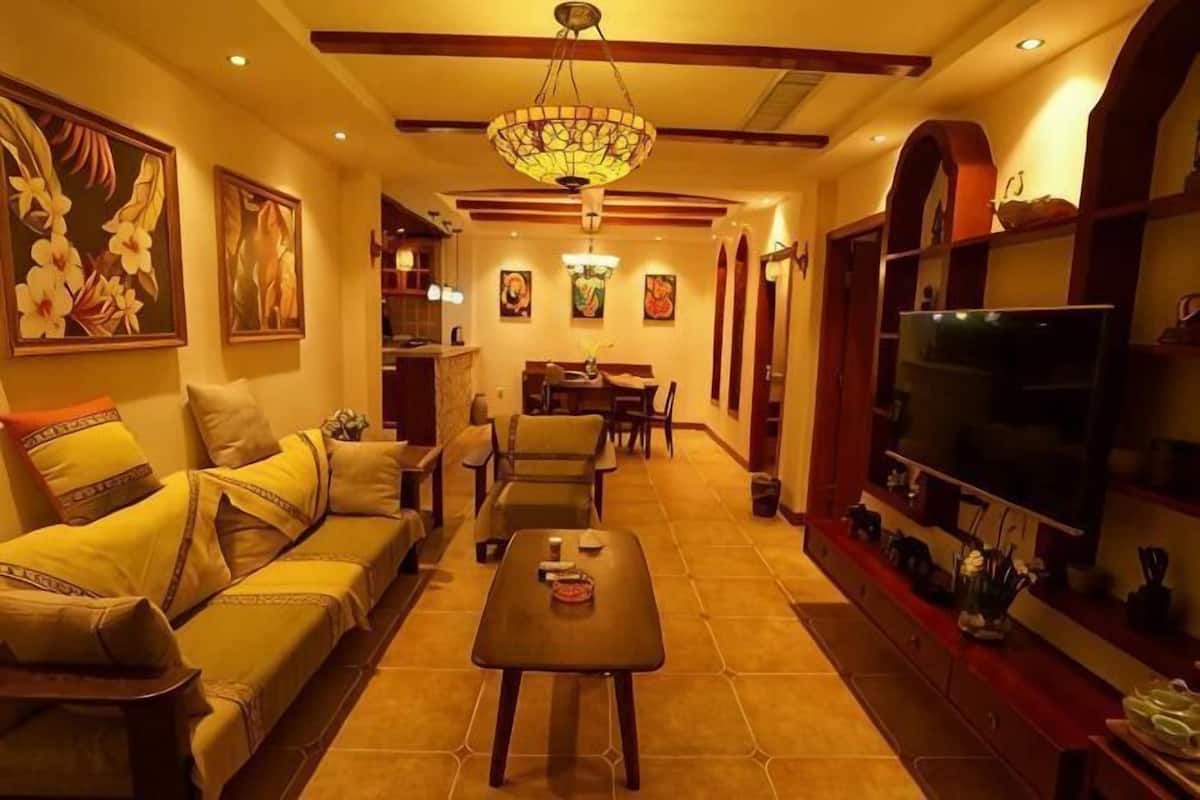 A living room with a sofa, coffee table, TV, and artwork on the walls.